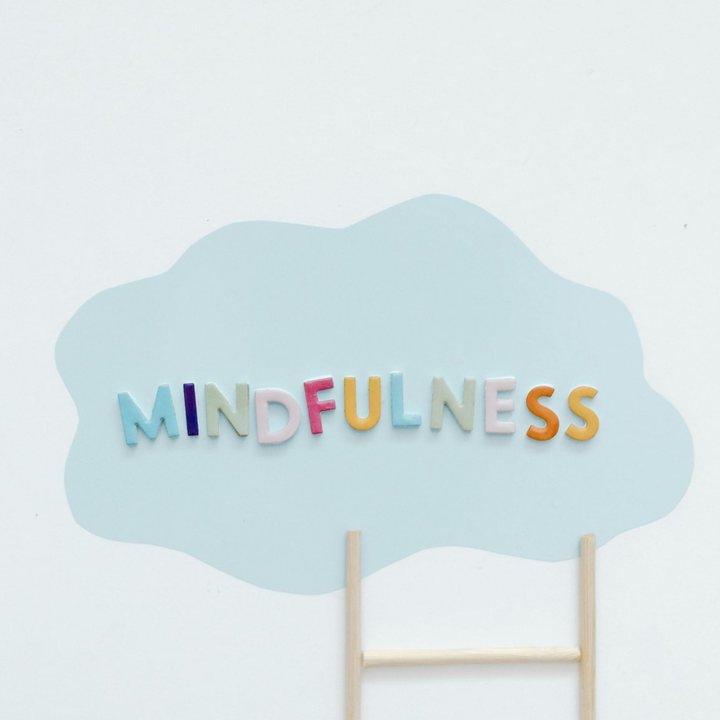 Het woord mindfulness op een blauw wolkje met een houten laddertje